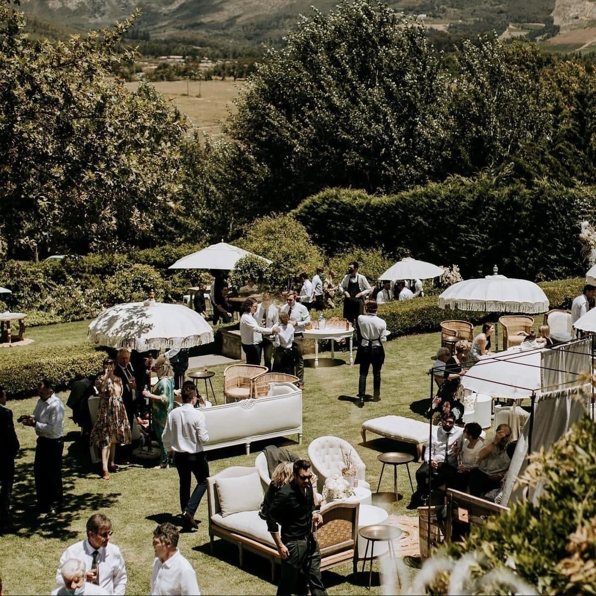 Guests gathered in a garden lounge setup during a wedding reception.
